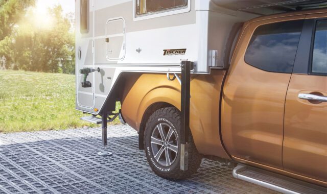 Detailansicht der Tischer-Kabine beim Absetzen auf ein goldenes Pickup-Fahrzeug, Fokus auf Stütze und Radkasten.