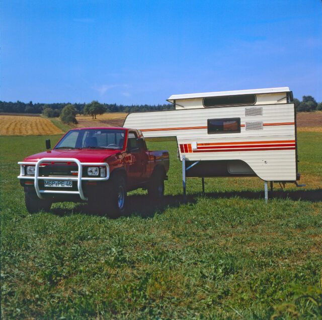 1986_Klassische Tischer-Kabine auf rotem Dodge RAM – aufgestellt auf grüner Wiese.