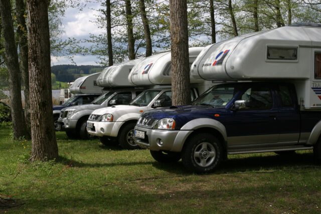 Reihe von Tischer-Kabinen auf Pick-ups im Wald – Fahrzeuge im Halbkreis aufgestellt.