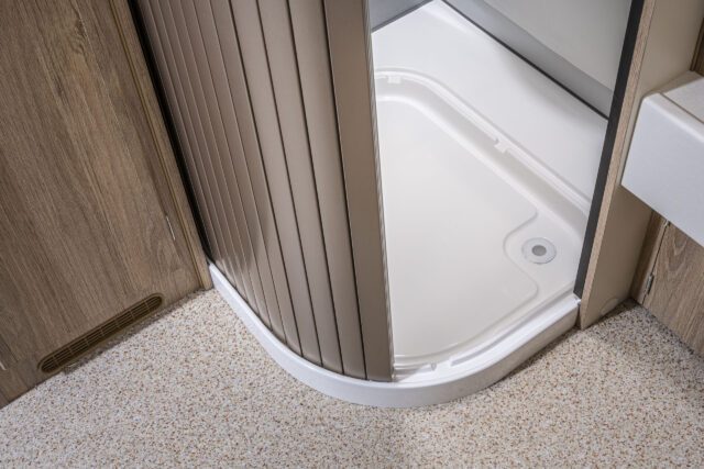 Eingezogene Duschtrennwand mit Blick auf Duschtasse im Bad der Tischer Wohnkabine.