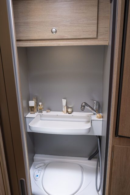 Waschbecken geöffnet, Kassettentoilette darunter – Badezimmer in Tischer Wohnkabine.