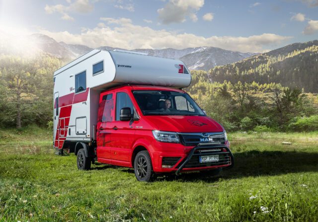 Außenaufnahme der Box 340S auf MAN TGE, rotes Fahrerhaus vor Bergkulisse.