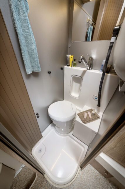 Kassettentoilette mit Duschbrause, Handtuch und Spiegelschrank in Tischer Kabine.