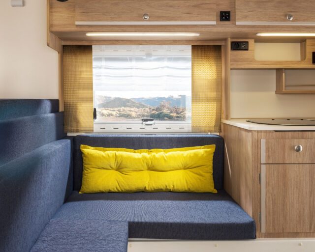 Tischer Kabine: Polster in Mittelgrau, gelbe Vorhänge, gelbes Kissen.