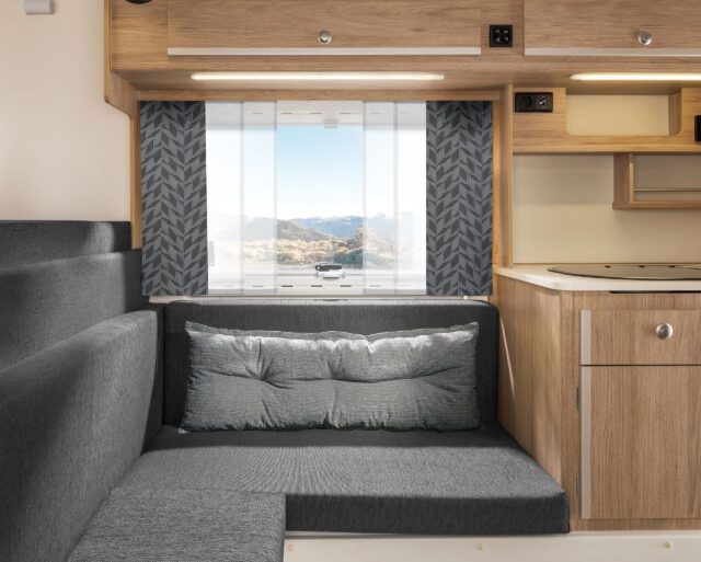 Sitzbereich mit anthrazitfarbenen Polstern und gemusterten Vorhängen in Grau.