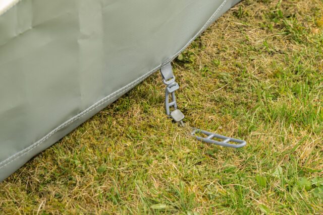 Erdabspannung mit Clip-System am unteren Rand des Tischer Vorzelts auf Wiese.