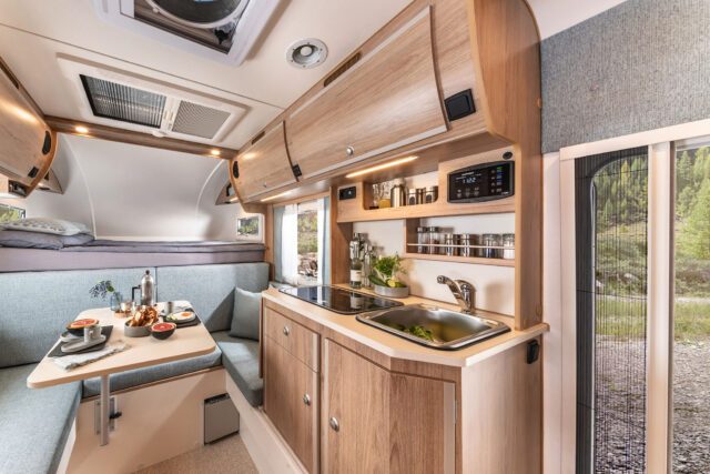 Innenraum der Tischer 260R/RS mit Küchenzeile, Sitzecke und Oberschränken in hellem Holzdesign.