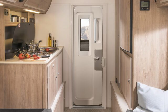 Blick durch Küchenzeile auf die Tür – Innenraum einer Tischer Wohnkabine.