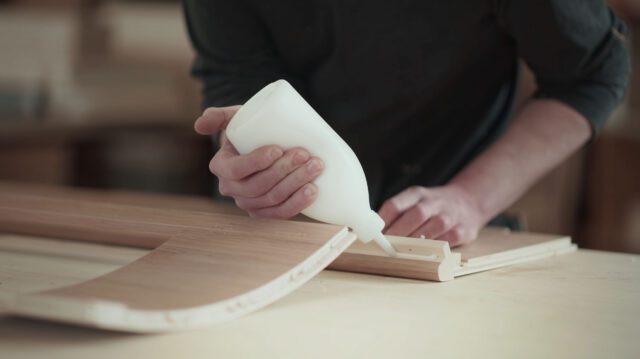 tischer_manufaktur_Auftrag von Holzleim auf ein geschwungenes Möbelelement.