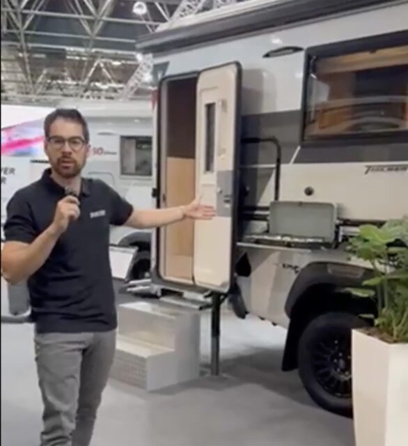 Tischer-Kabine auf Pickup, Mann spricht in Mikrofon – Szene auf Messestand.